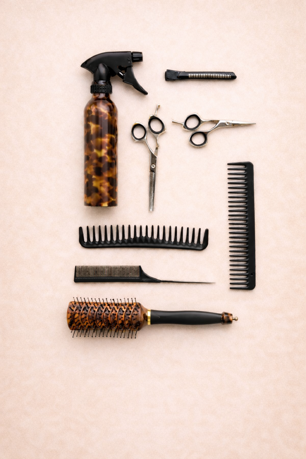 Hair styling tools, including scissors, combs, and a spray bottle, arranged on a beige surface.