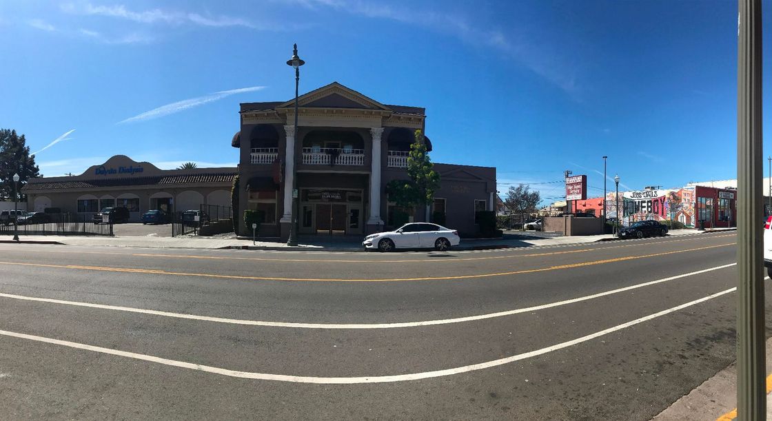 A street-level panorama shows a historic-style commercial building with a central portico, surrounded by a sunny parking lot.
