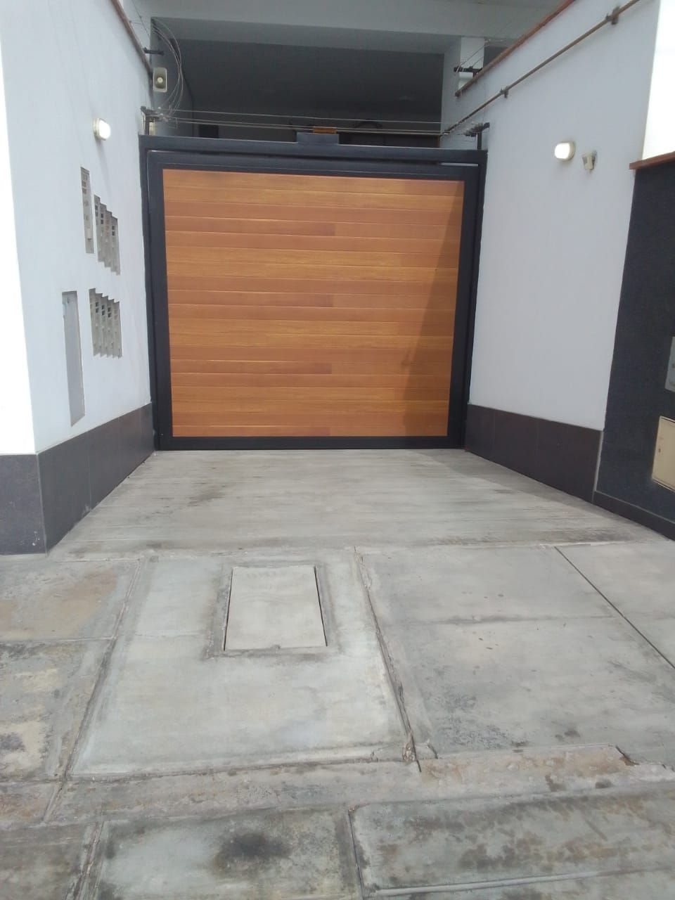 Puerta de madera con marco negro empotrada en hormigón.