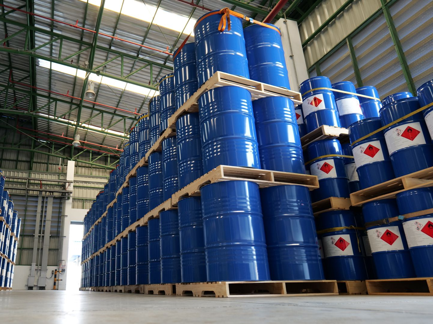 Rows of blue industrial drums stacked on pallets inside a warehouse