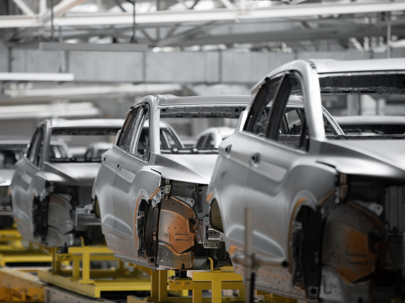 Car assembly line with unfinished silver cars in a factory