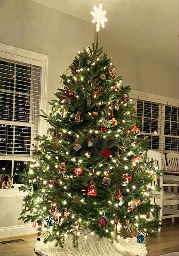 A christmas tree is sitting in a living room next to a window.