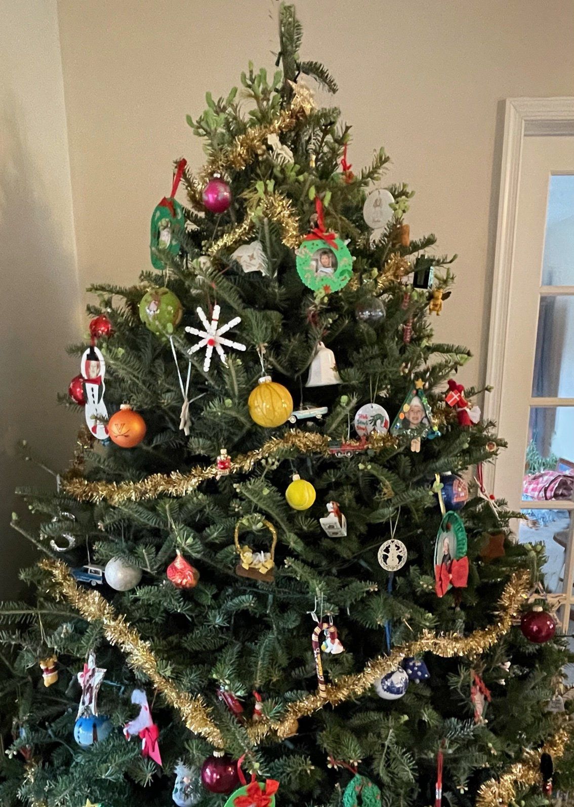 A christmas tree is decorated with lots of ornaments and tinsel.