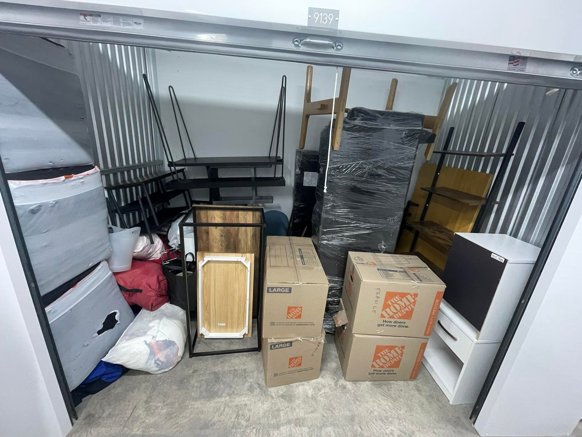 Storage unit filled with boxes, furniture, and miscellaneous items.