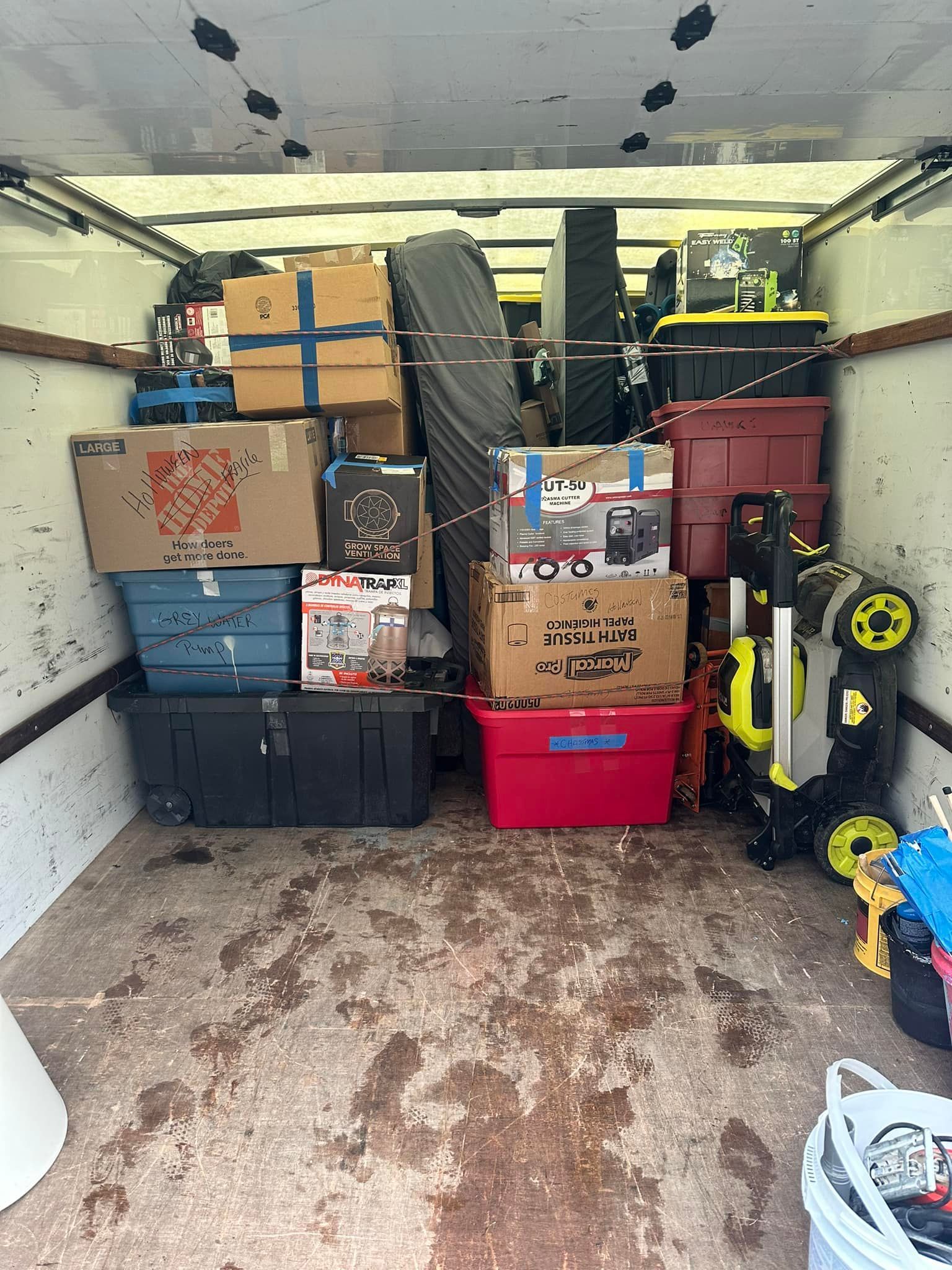 Truck bed packed with boxes, tools, and containers; moving day.