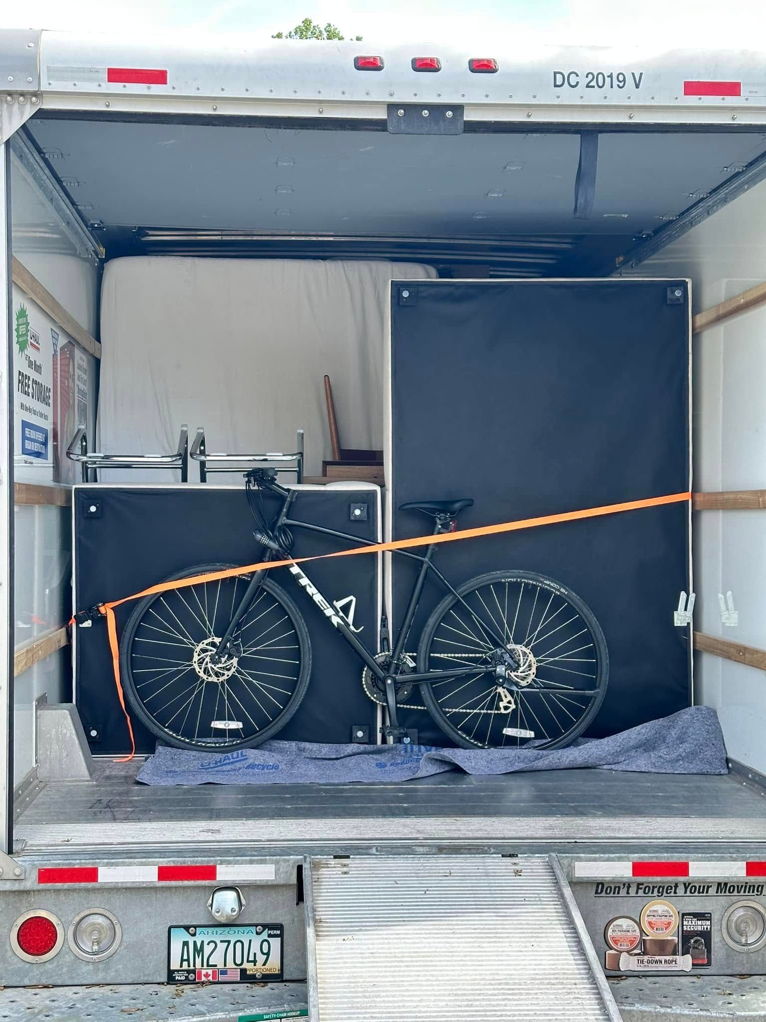 A bicycle secured in a moving truck, along with other items, ready for transport.
