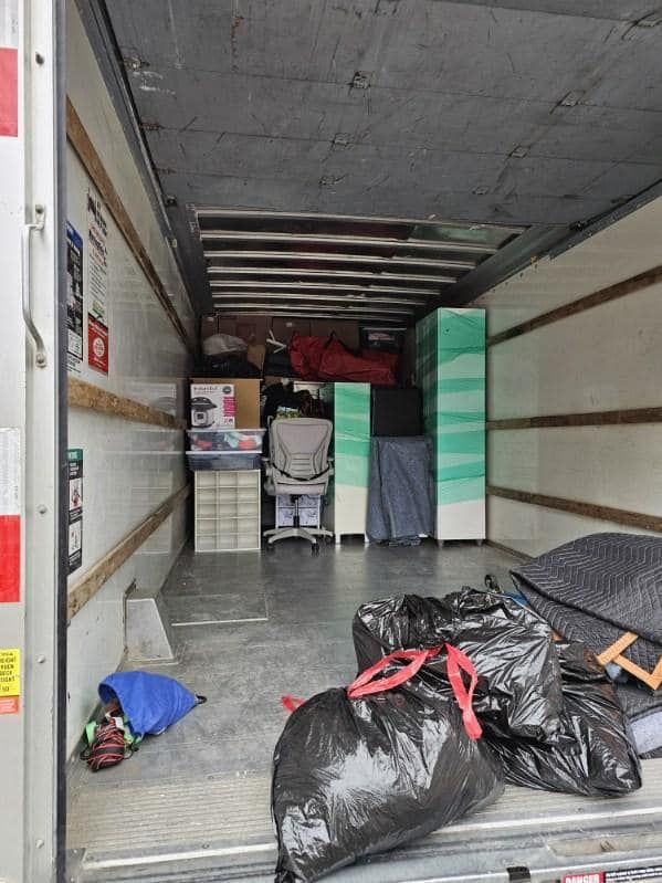 Interior of a moving truck filled with furniture, boxes, and bags.