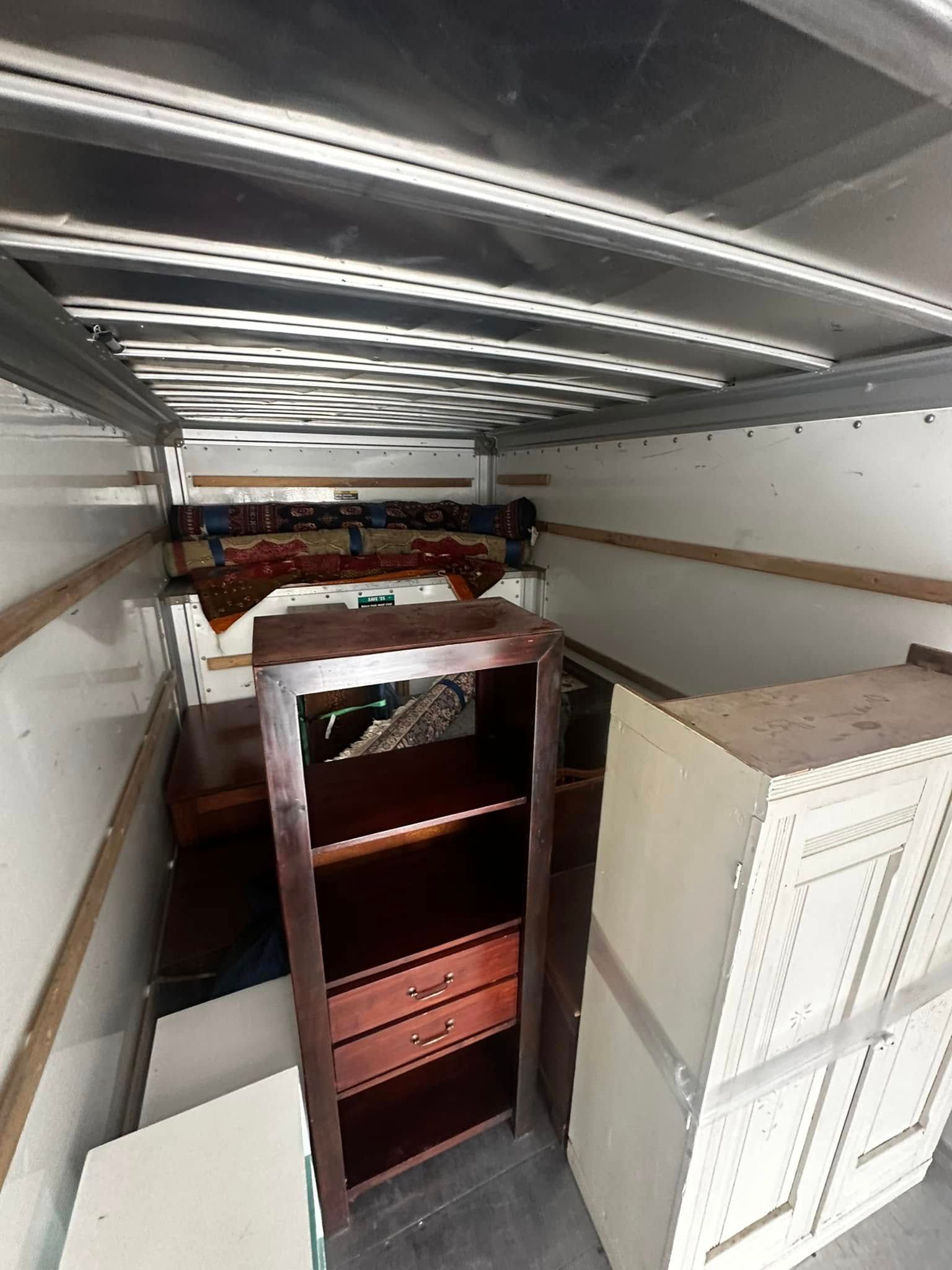 Inside of a moving truck: furniture, including bookshelves and cabinets, loaded for transport.