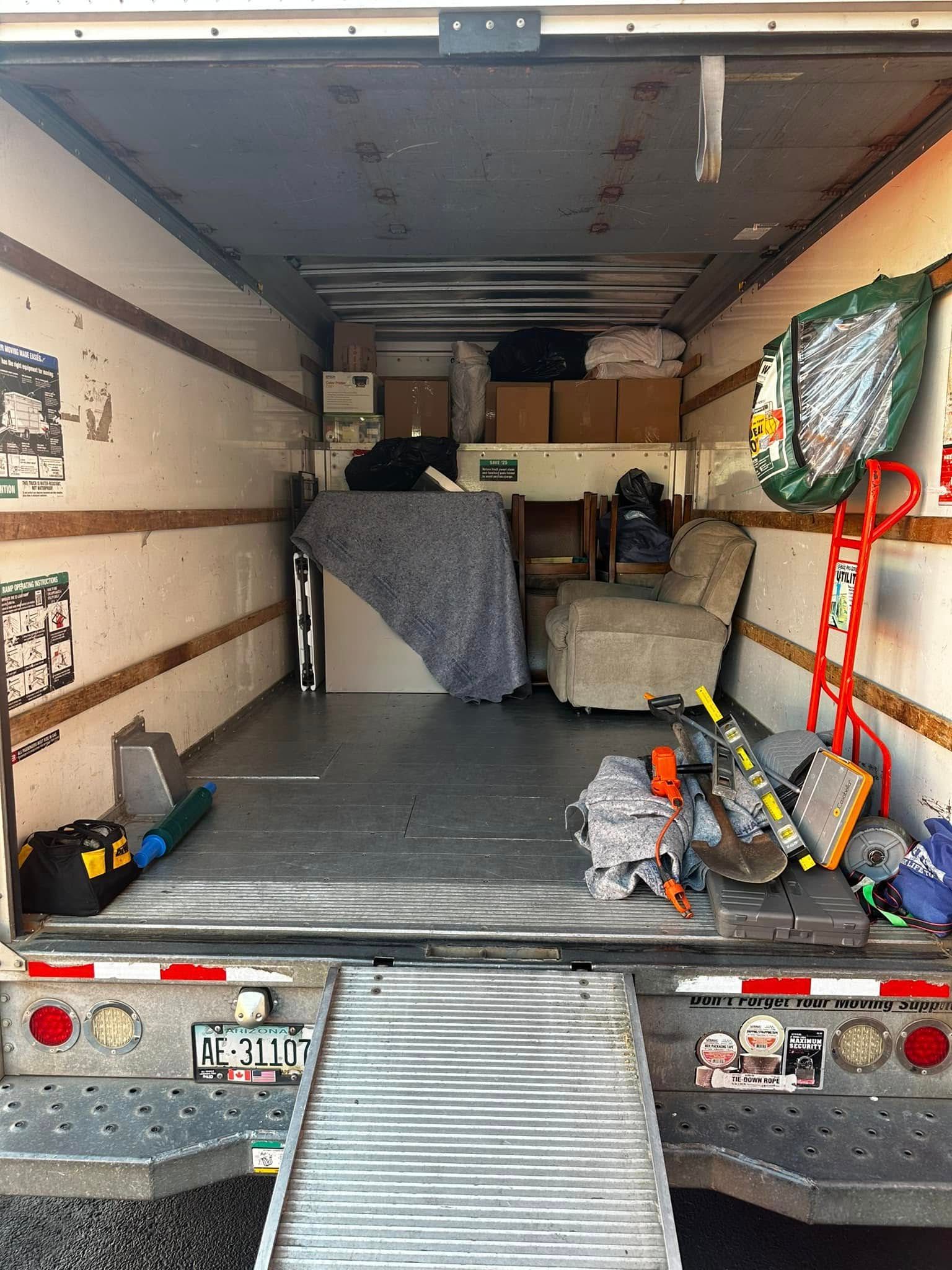 An open moving truck bed with furniture and boxes inside, ramp down.