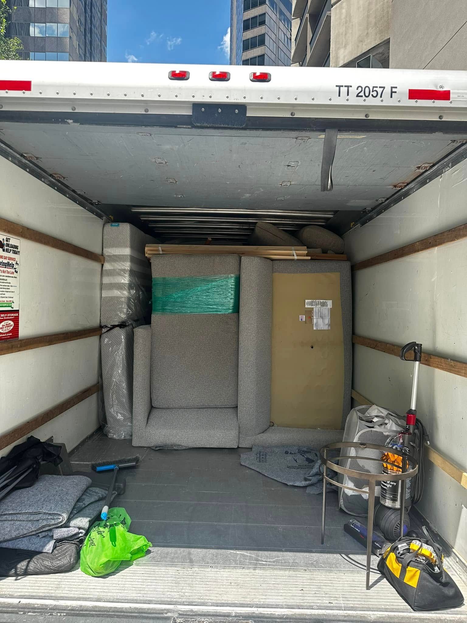 Inside a moving truck, furniture wrapped for transport.