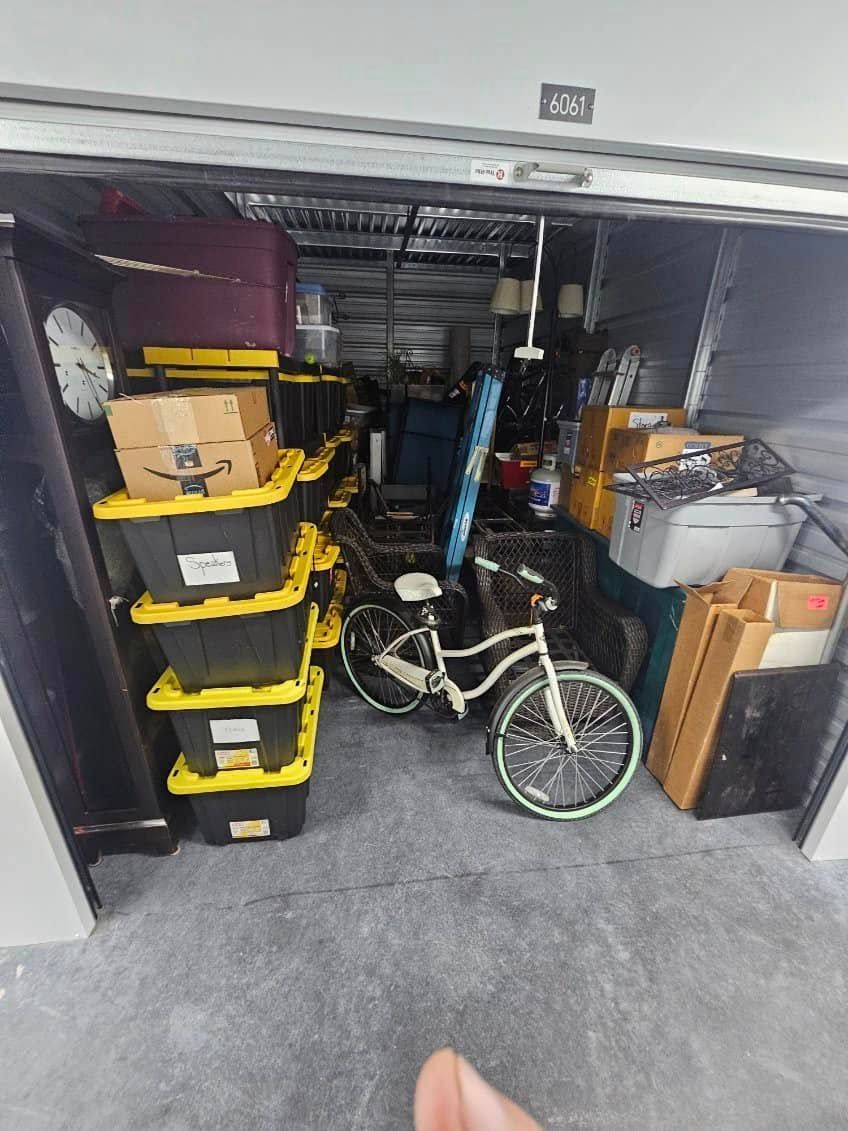A storage unit packed with boxes, a bicycle, and various items; interior view.