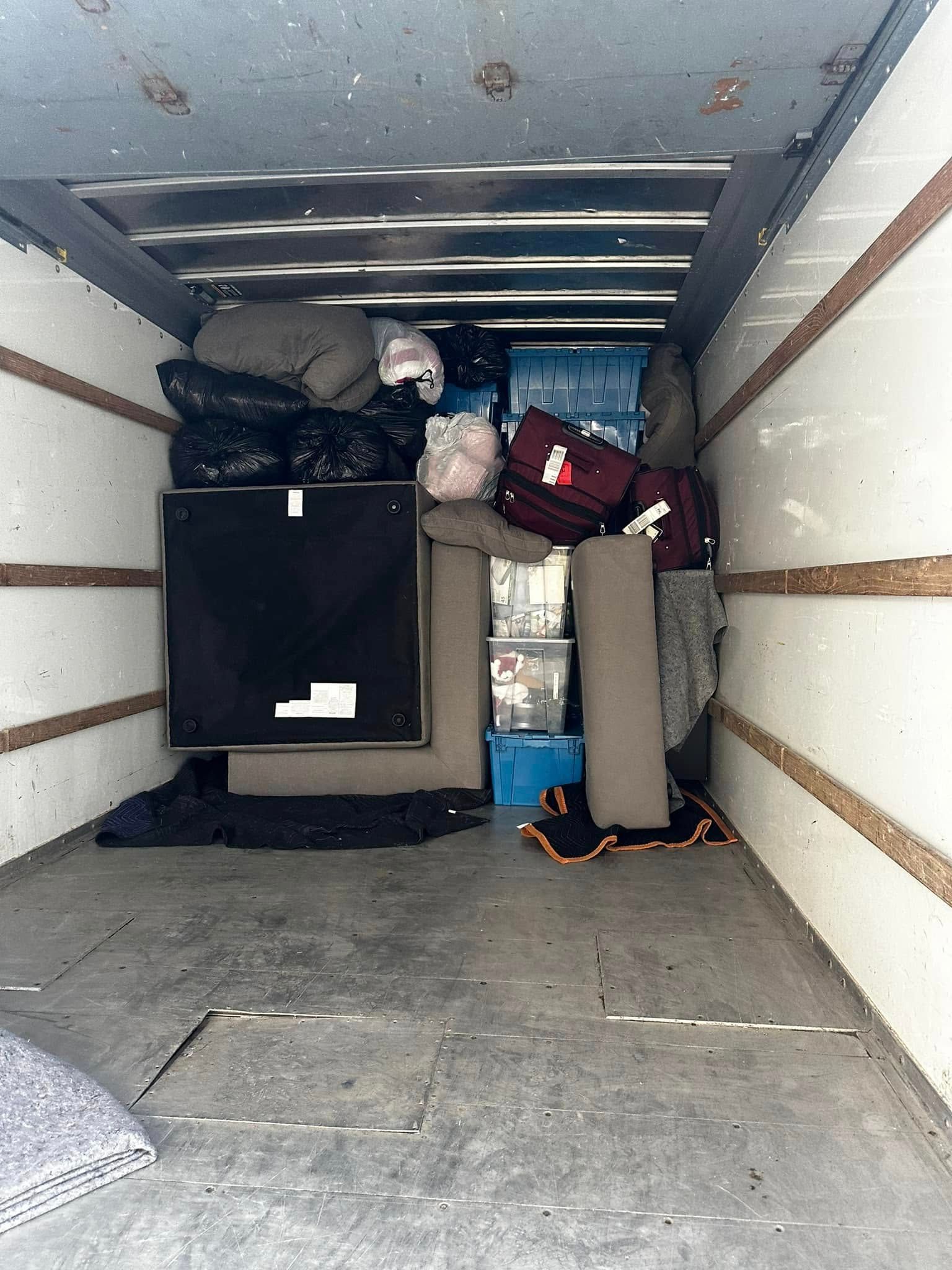 Inside of a moving truck, packed with furniture and boxes of various sizes and colors.