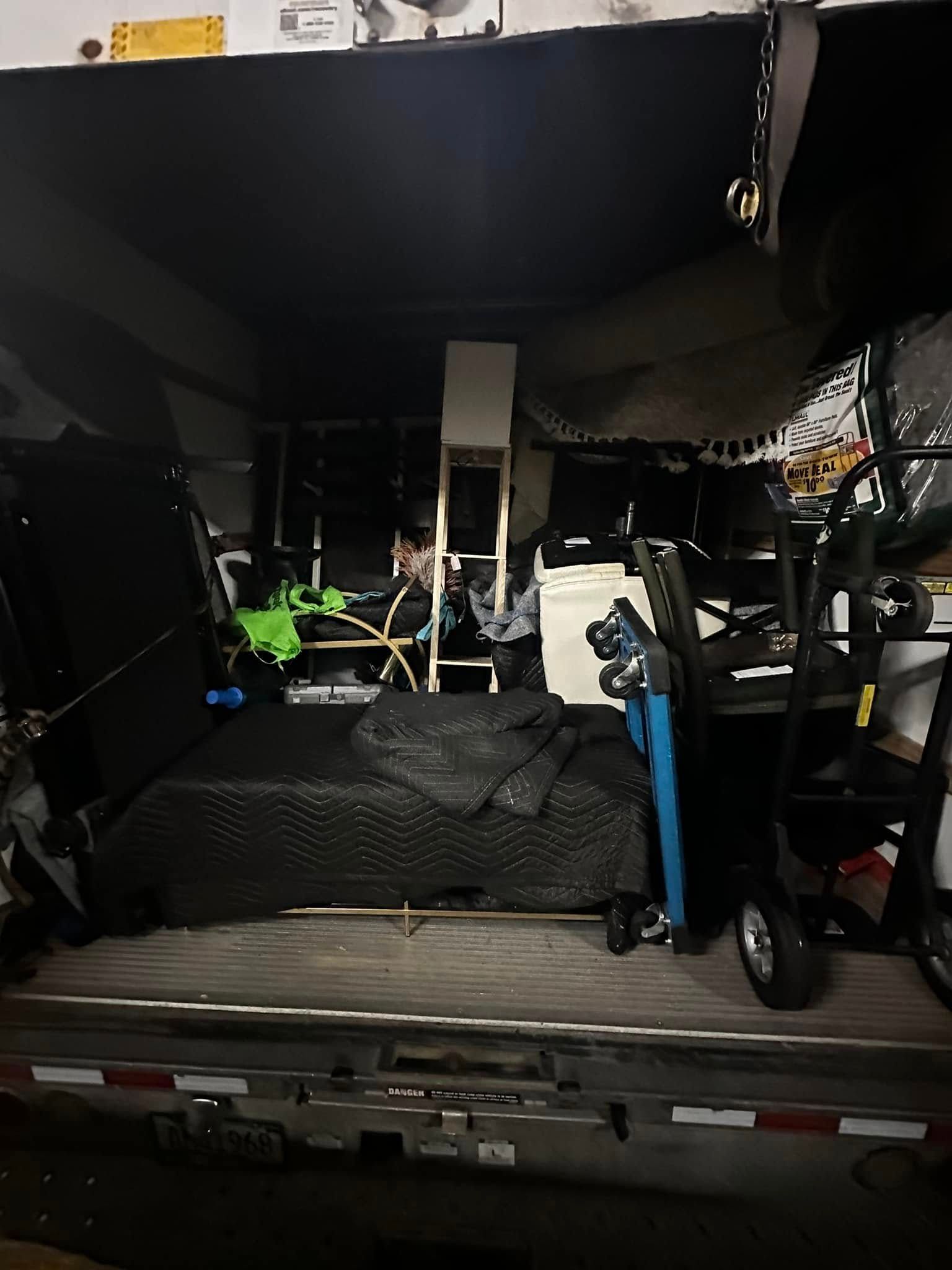 Interior of a cluttered truck, filled with equipment and a chair.