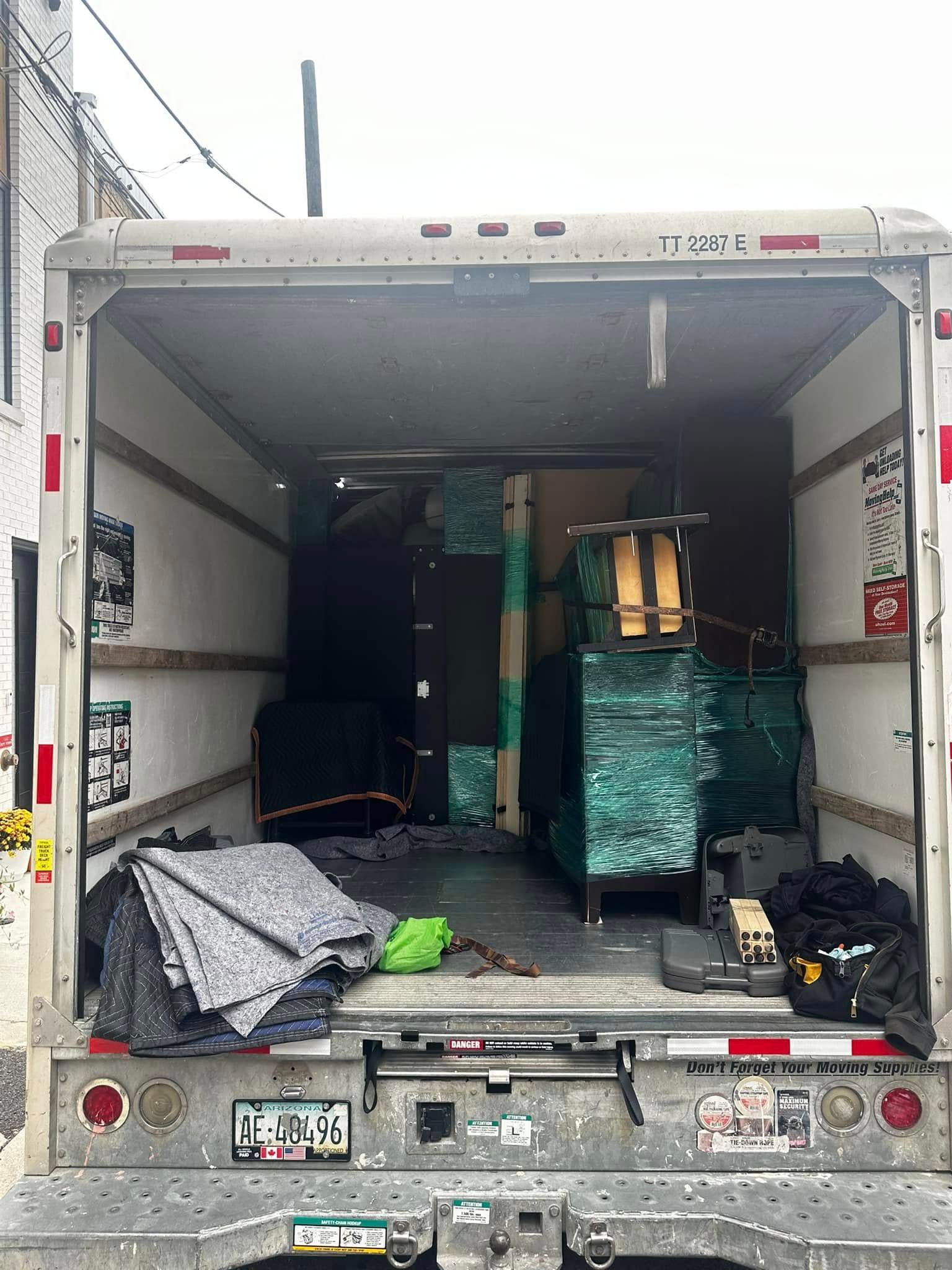 Inside a box truck, furniture and moving pads are loaded.