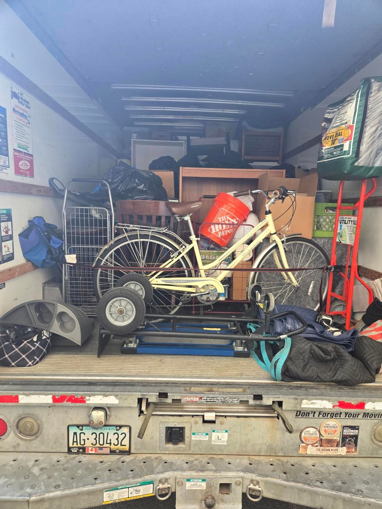 A loaded moving truck with a bicycle, furniture, boxes, and bags.
