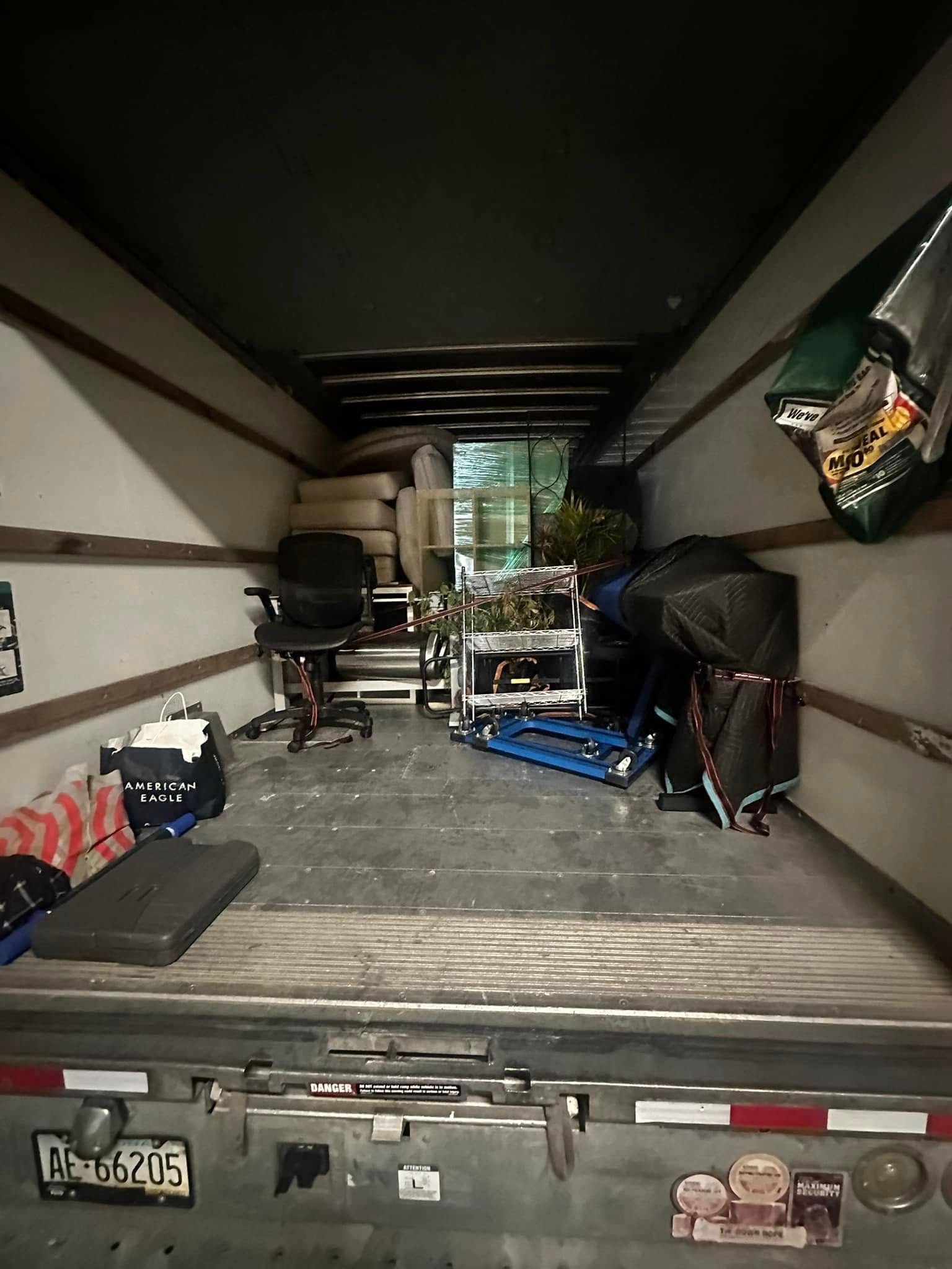 Inside a moving truck: furniture, boxes, and other items ready for transport.
