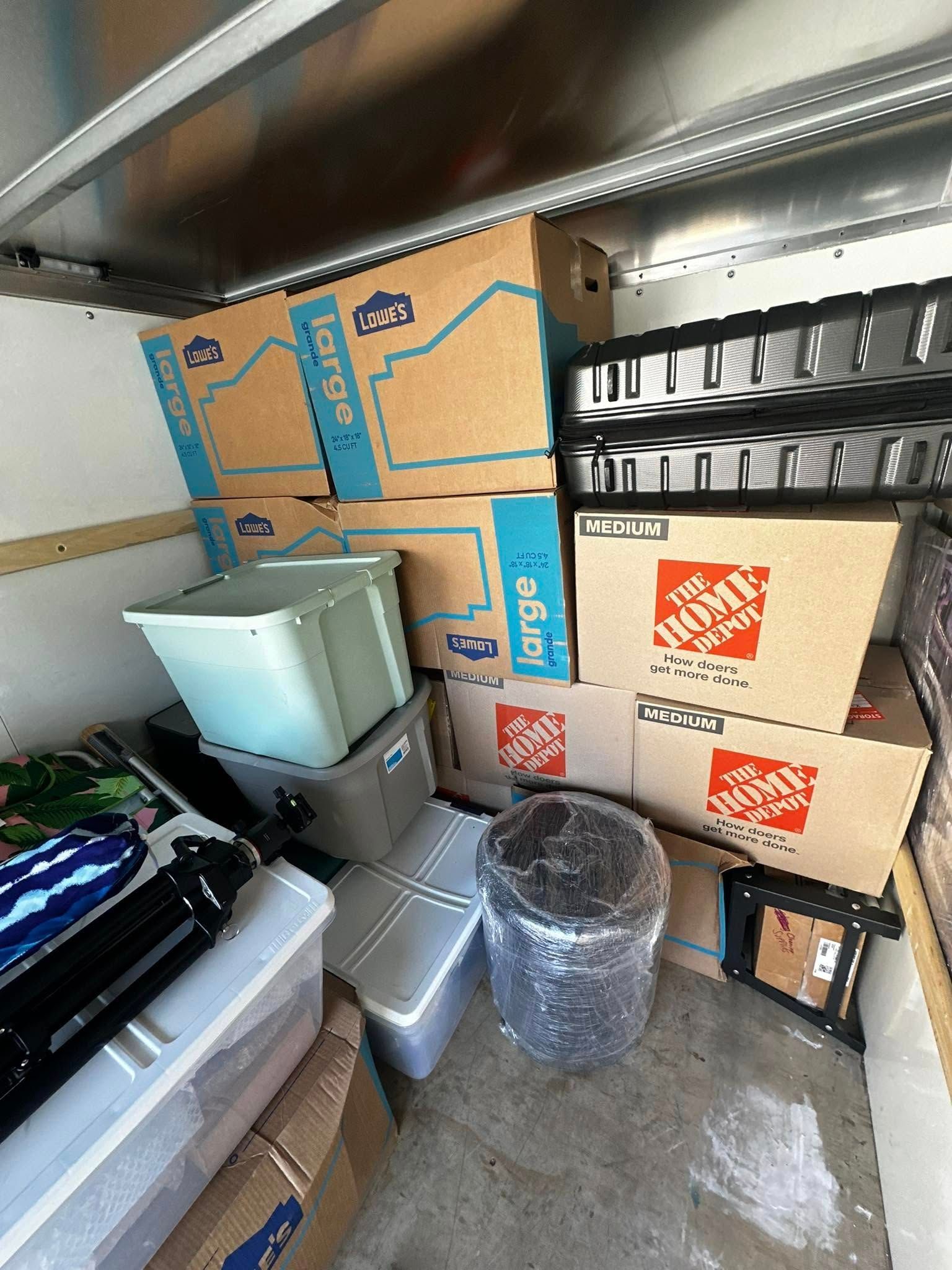 Boxes and bins fill the inside of a moving truck, including Home Depot and Lowe's boxes.
