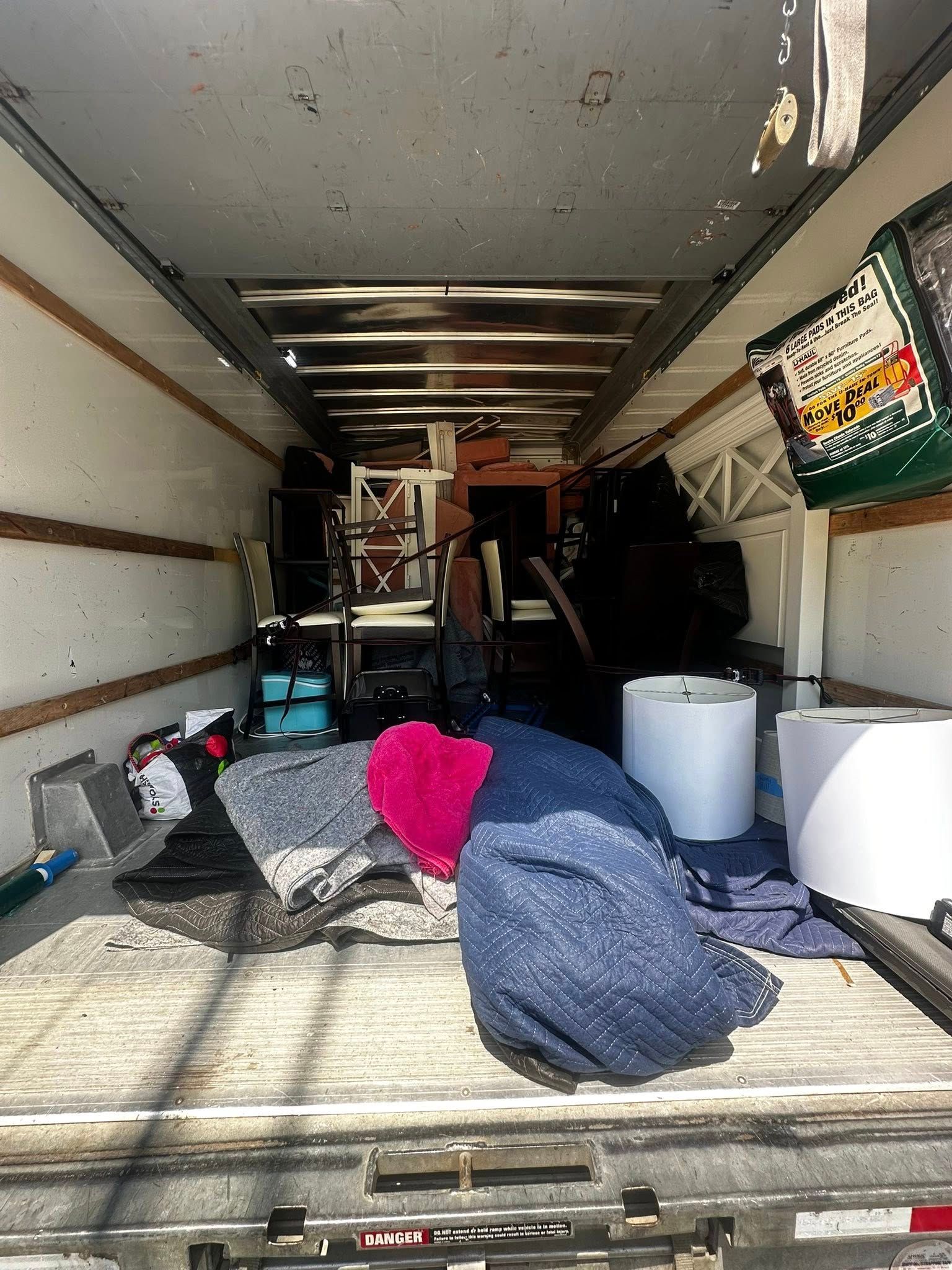Inside a moving truck, filled with furniture and packed items, ready to be transported.