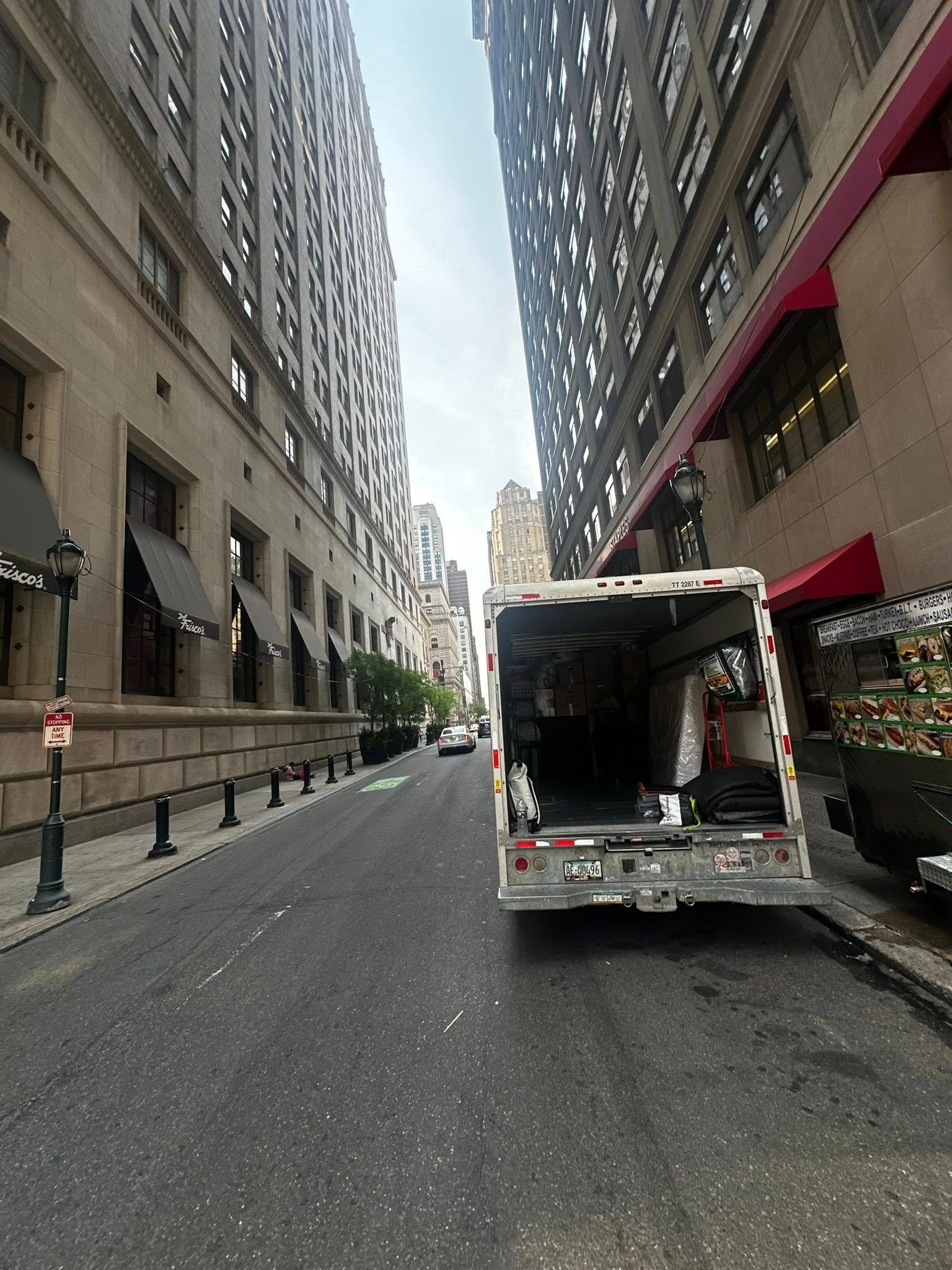 A truck parked on a city street with tall buildings on either side.