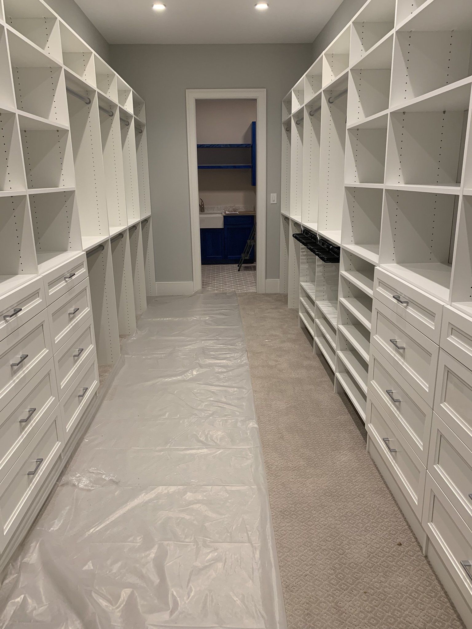 A walk in closet with lots of shelves and drawers.