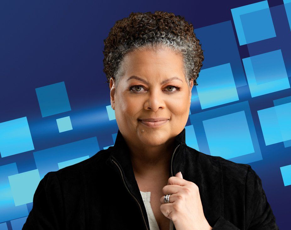 Woman in black jacket, smiling, blue background with blue squares.