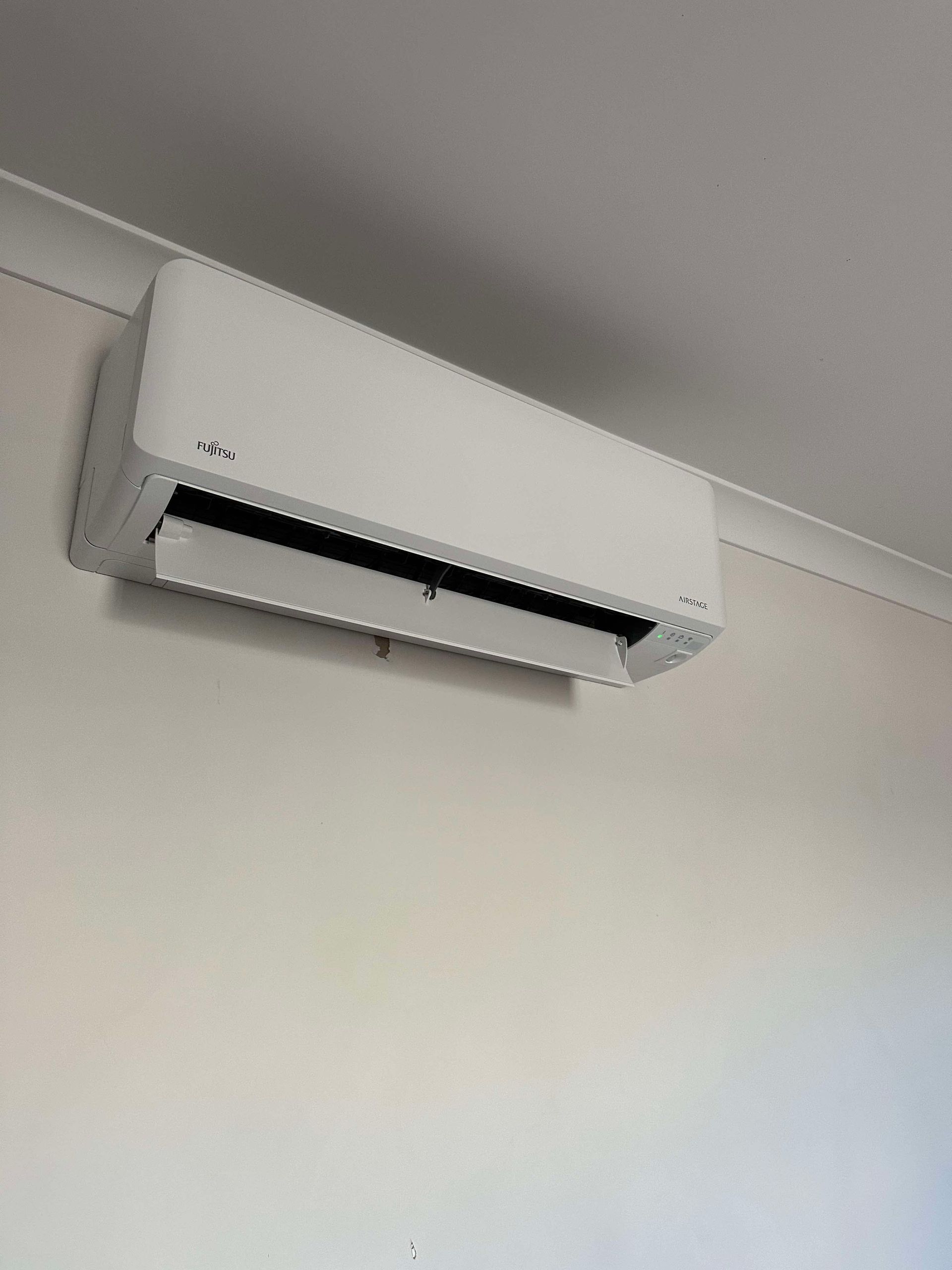 A white air conditioner is hanging from the ceiling in a room.