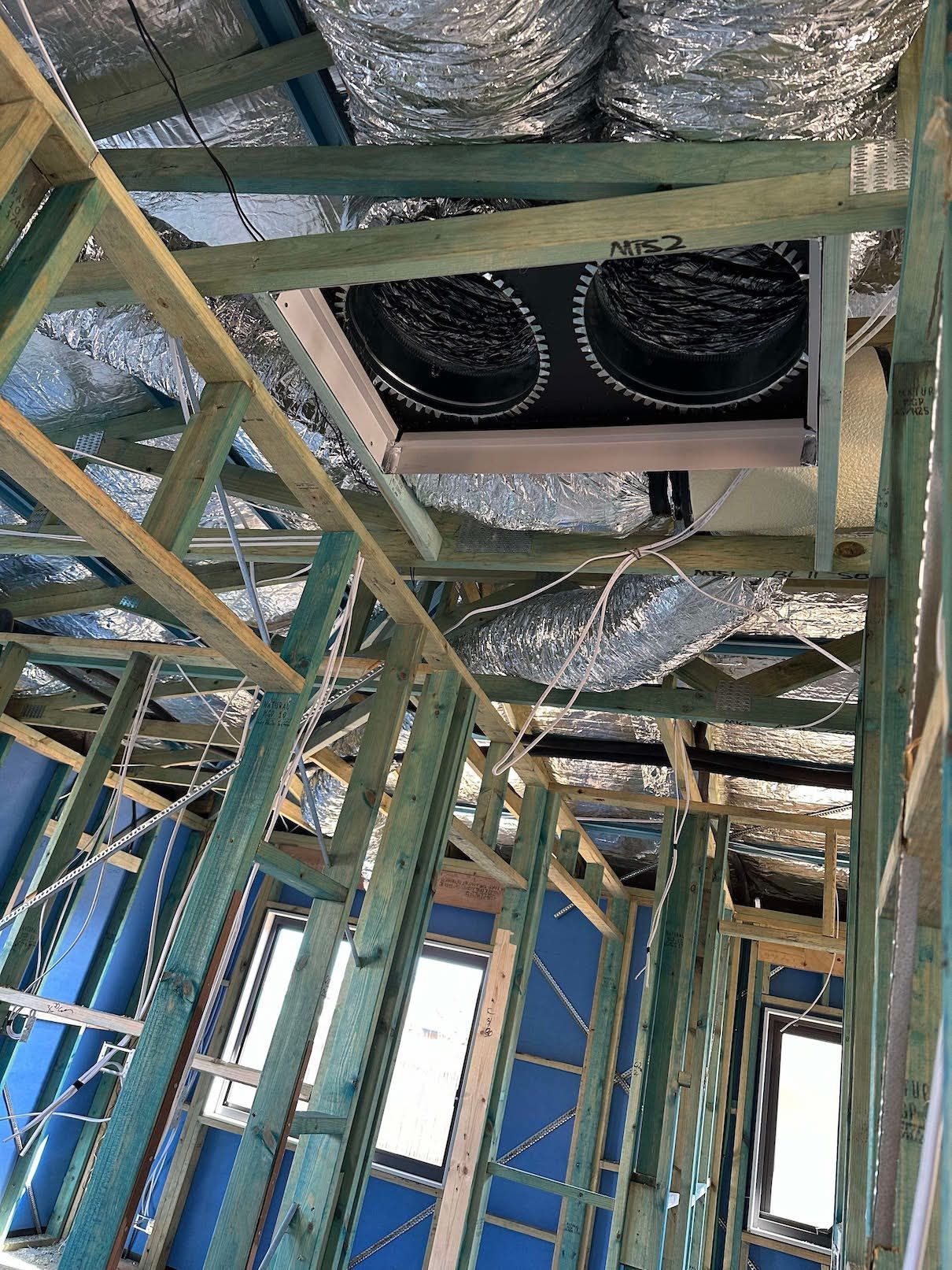 A room in a house under construction with a ceiling fan.