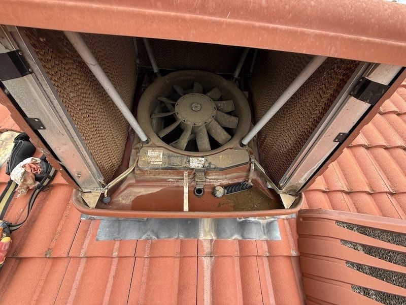 A fan is sitting on top of a red tiled roof.