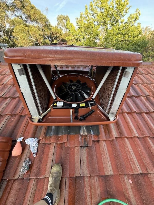 A person is standing on a roof next to a fan.
