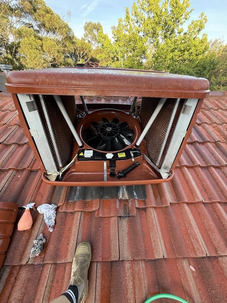 A person is standing on a roof with a fan on it.