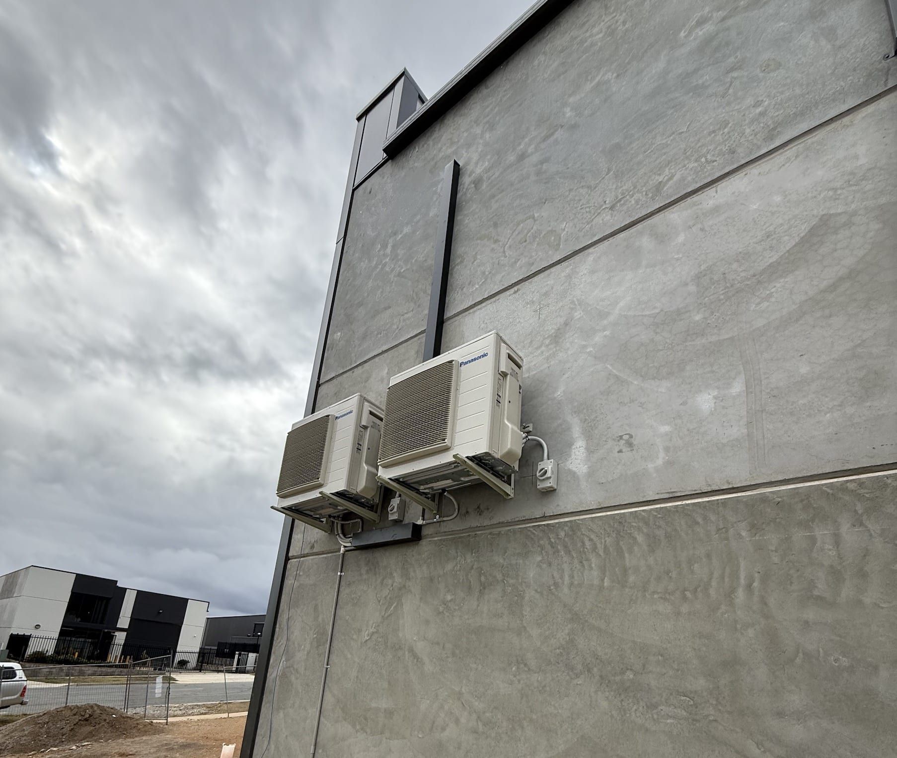 Two air conditioning units mounted on a gray concrete building.