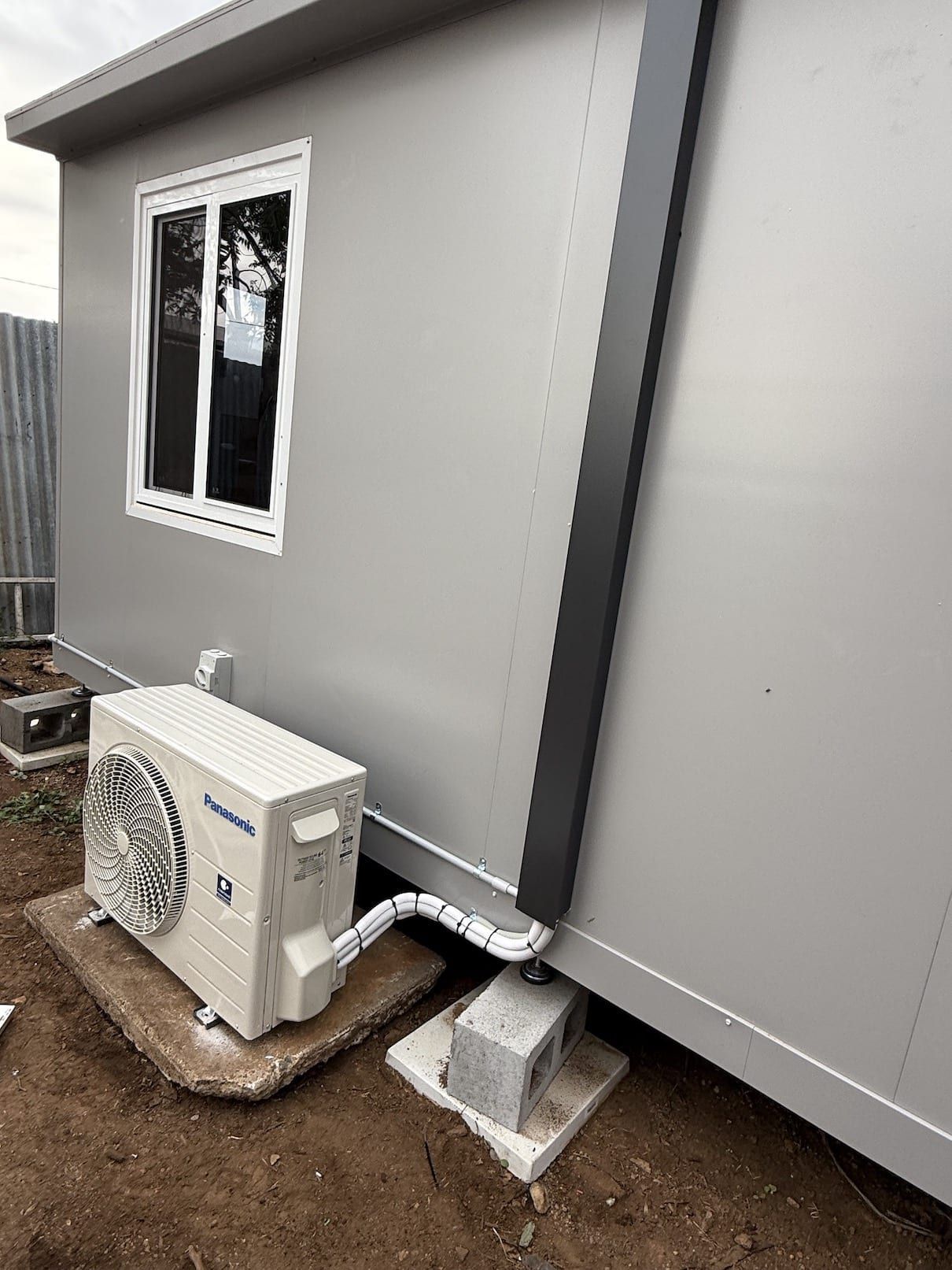 A small air conditioner is sitting on the side of a building.