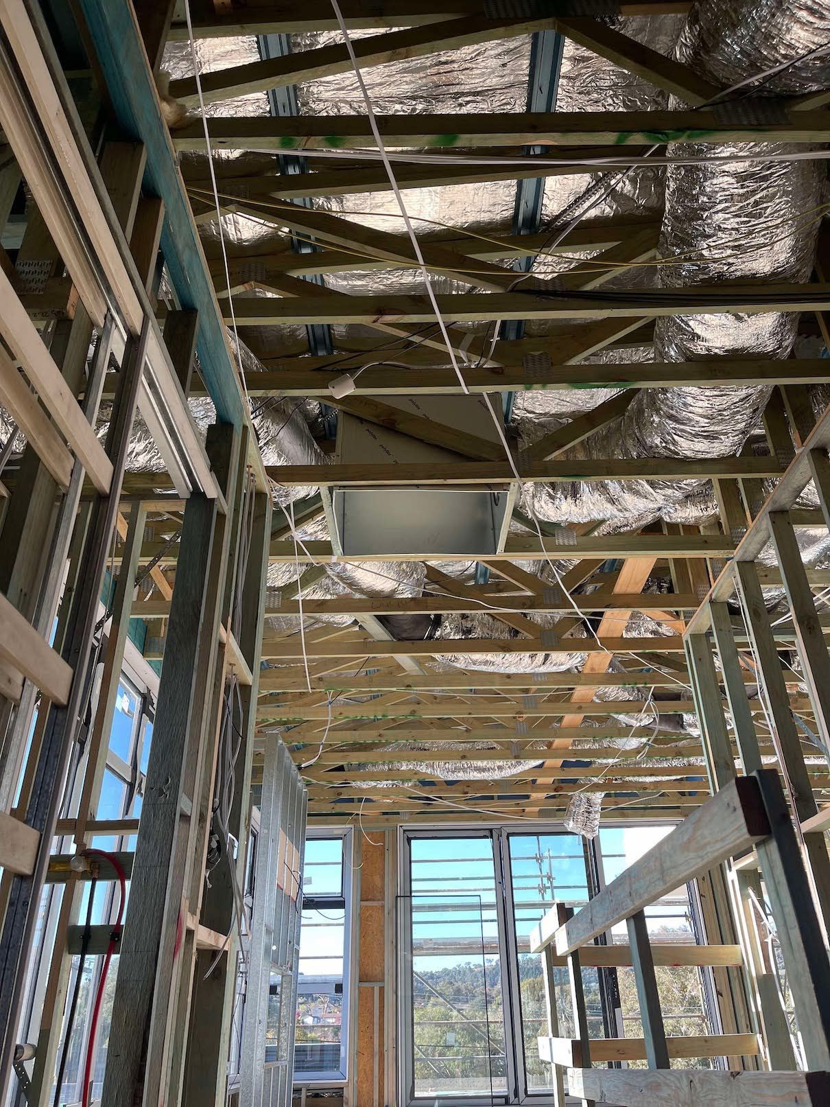 A building under construction with a lot of wooden beams and pipes hanging from the ceiling.