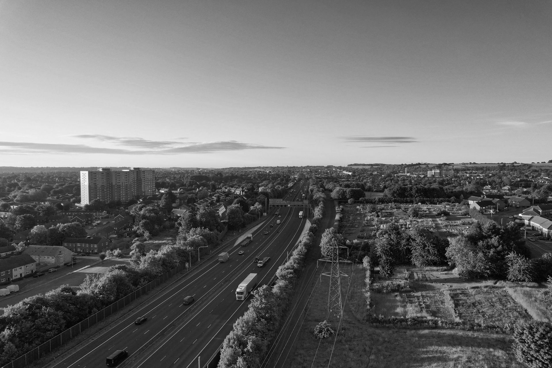 Overhead view of a town with houses, trees, and buildings, under a clear, blue sky.