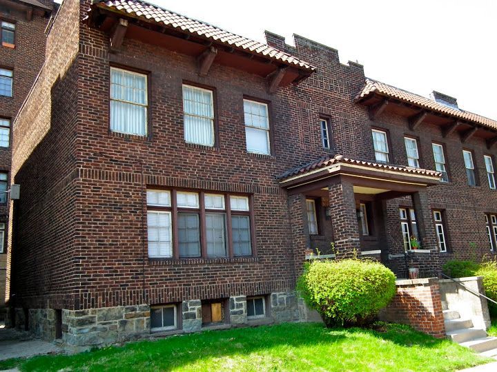 Brick building with multiple windows, tile roof, small porch, and green lawn.