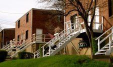 Brick townhouses with white staircases leading to entrances on a hillside.
