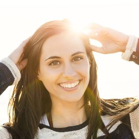 a woman in a sweater is smiling and touching her hair