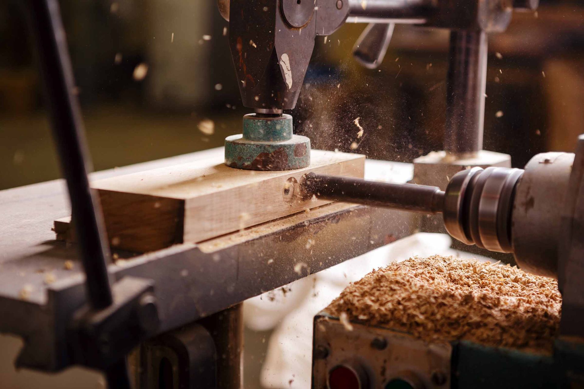 Woodworking lathe shaping a wooden block, with sawdust flying in a workshop