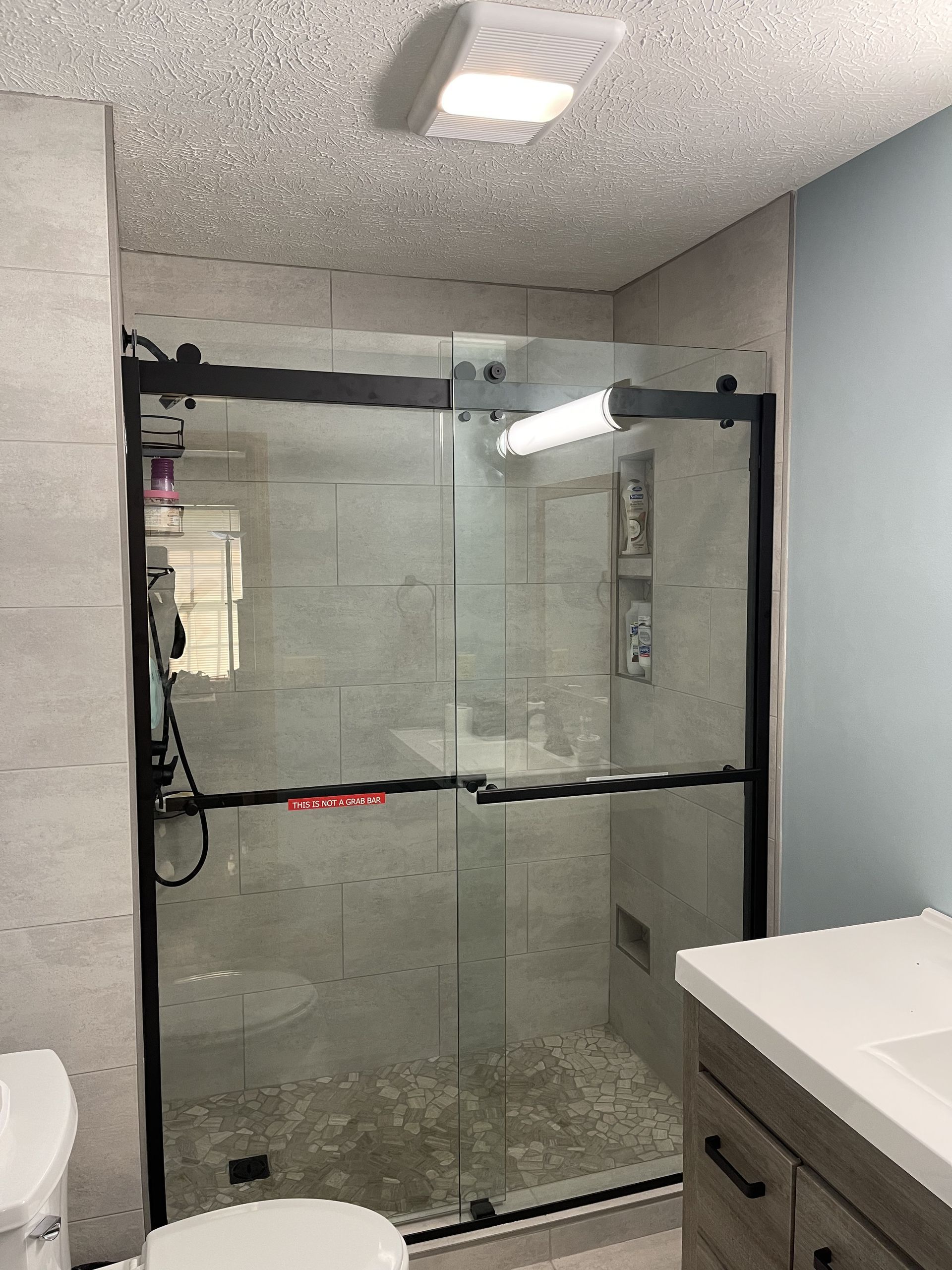 A bathroom with a sliding glass shower door and a toilet.
