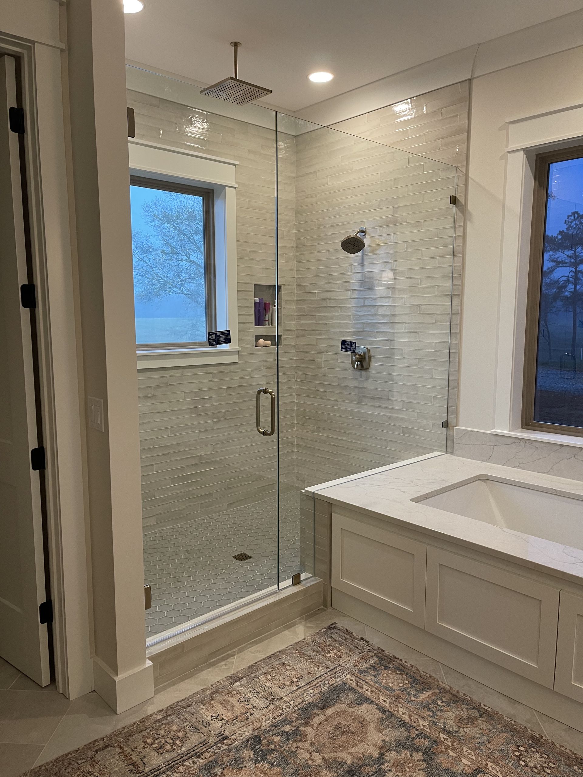 A bathroom with a walk in shower , sink , and window.