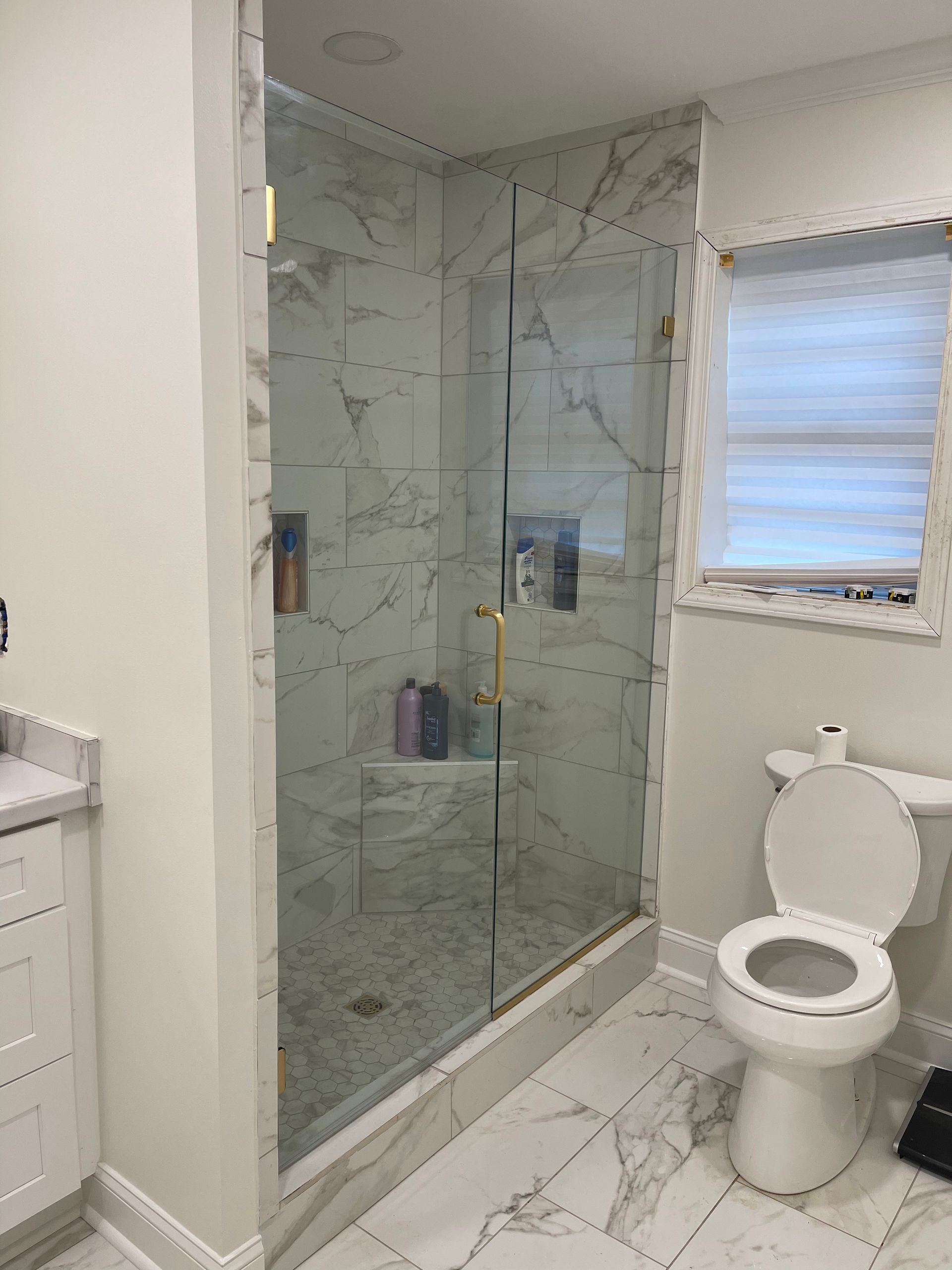 A bathroom with a toilet , shower and window.