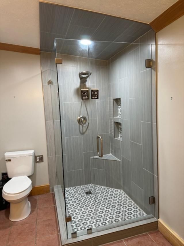 A bathroom with a toilet and a shower with a glass door.