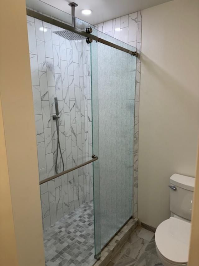 A bathroom with a sliding glass shower door and a toilet.