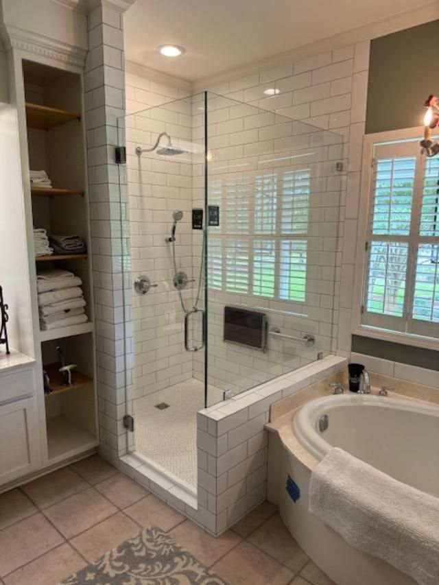 A bathroom with a tub , shower , and window.