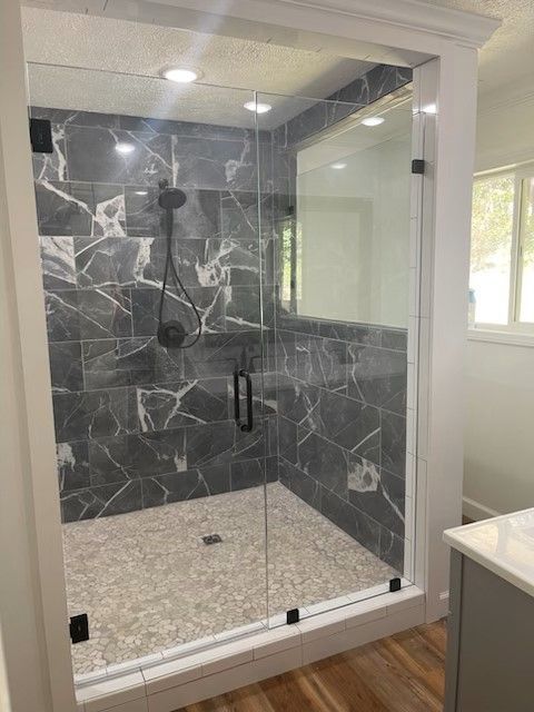 A bathroom with a walk in shower with a glass door.