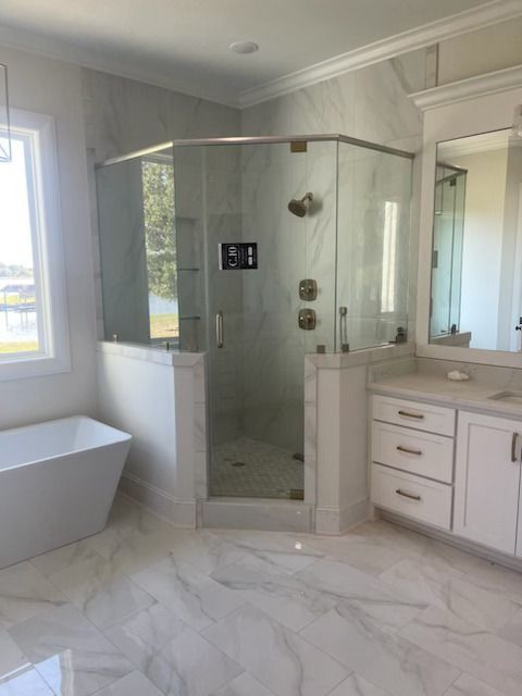 A bathroom with a tub , sink , shower and mirror.