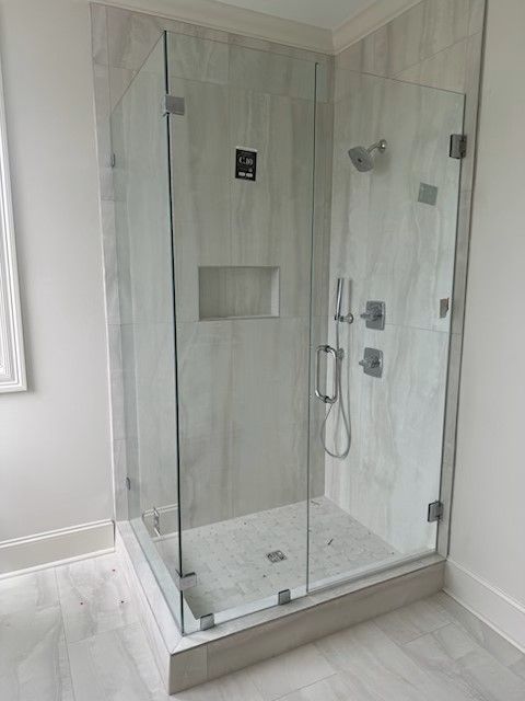 A bathroom with a walk in shower with a glass door.