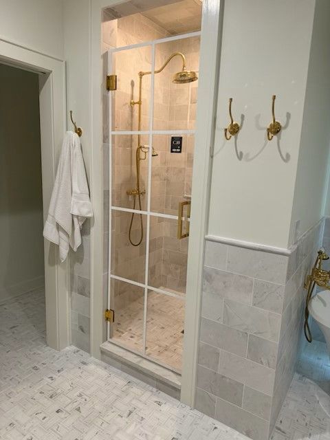 A bathroom with a walk in shower with a glass door.