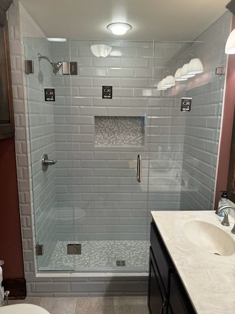 A bathroom with a walk in shower and a sink.