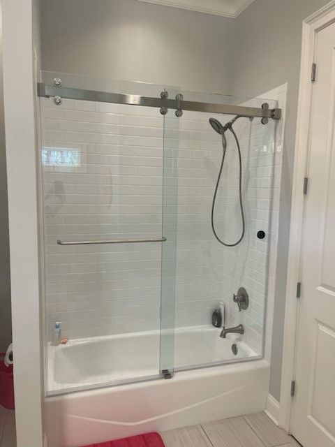A bathroom with a sliding glass shower door and a bathtub